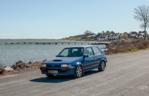 Løbsleder for Sports Motor Klubben Gladsaxes løb den 10. maj, Kim Bach Sørensen, ses her i den fine Toyota Corolla GT fra 1986. Sammen med datteren Freja Damgaard Sørensen passerer de her Dyreborg på Fyn under årets 1. afdeling.